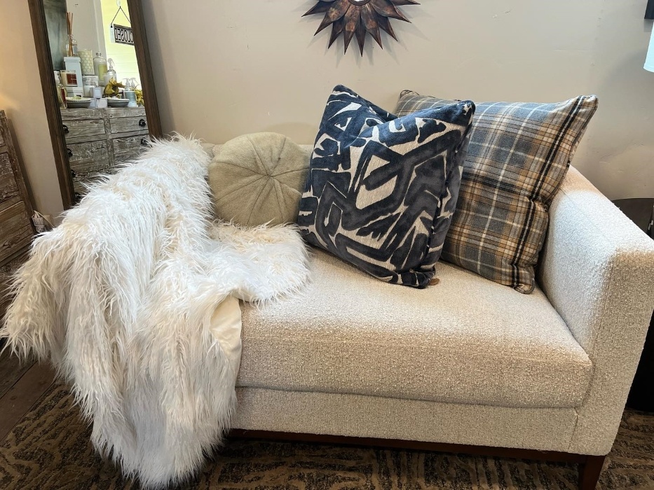 living room loveseat with pillows and a throw blanket